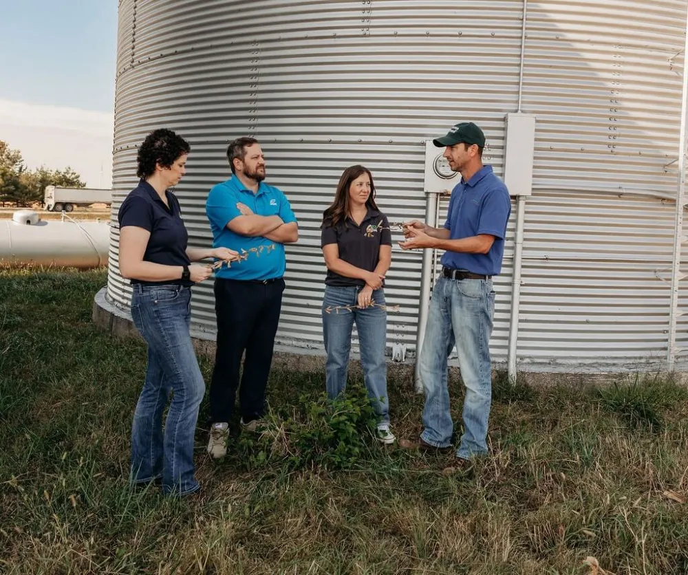 Farmers standing next to a silo discussing their crops 