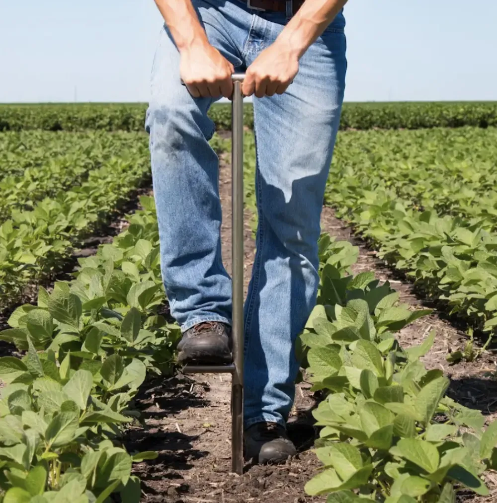 A farmer digging to plant crops in his field. 